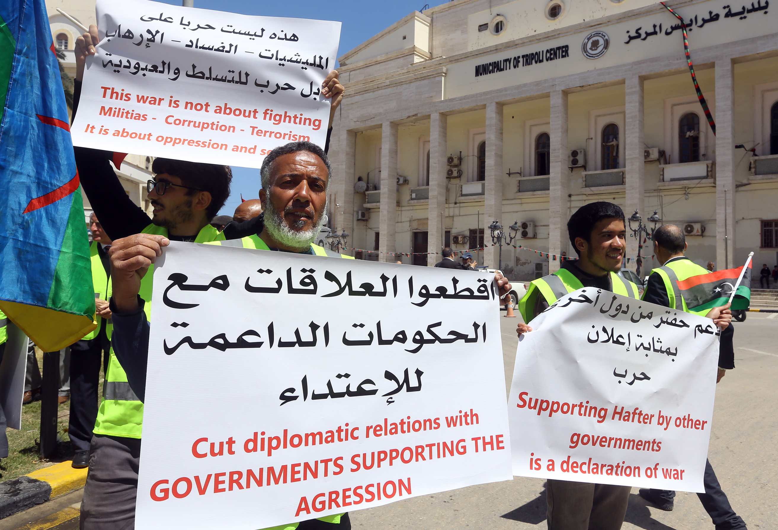 Libyan demonstrators hold signs against what they call foreign intervention in Libya, during a protest outside the municipality of Tripoli, on April 16, 2019 (AFP)