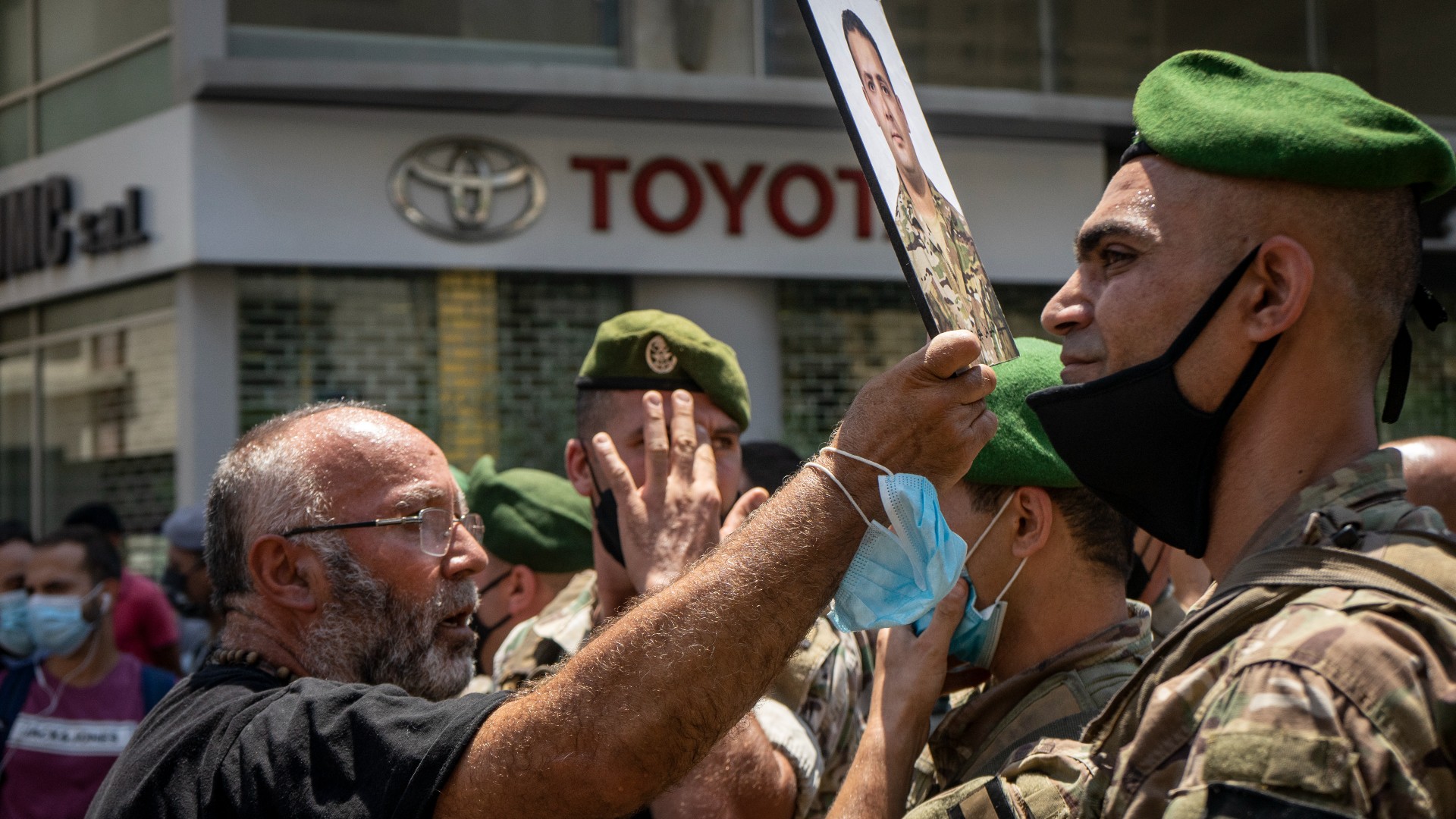 Un hombre sostiene una fotografía de un pariente muerto en la explosión del puerto de Beirut durante una protesta el 9 de julio de 2021 (MEE/Matt Kynastan)