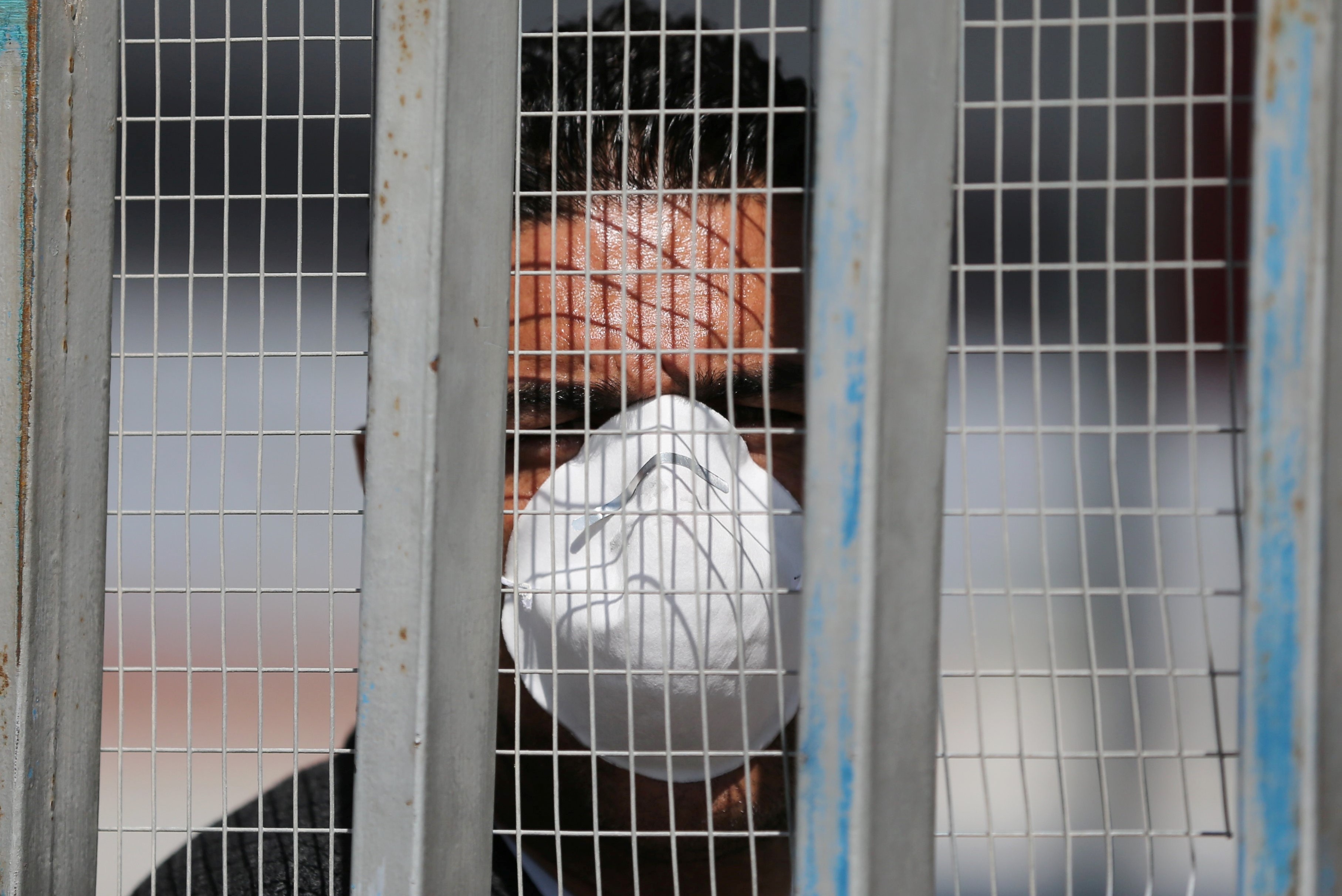 A man, wearing a mask amid coronavirus precautions, waits at Rafa border crossing on 8 March (Reuters)