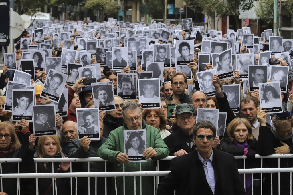 People hold pictures of the victims of the 1994 AMIA bombing during a commemoration in Buenos Aires on 18 July (Noticias Argentinas/AFP)