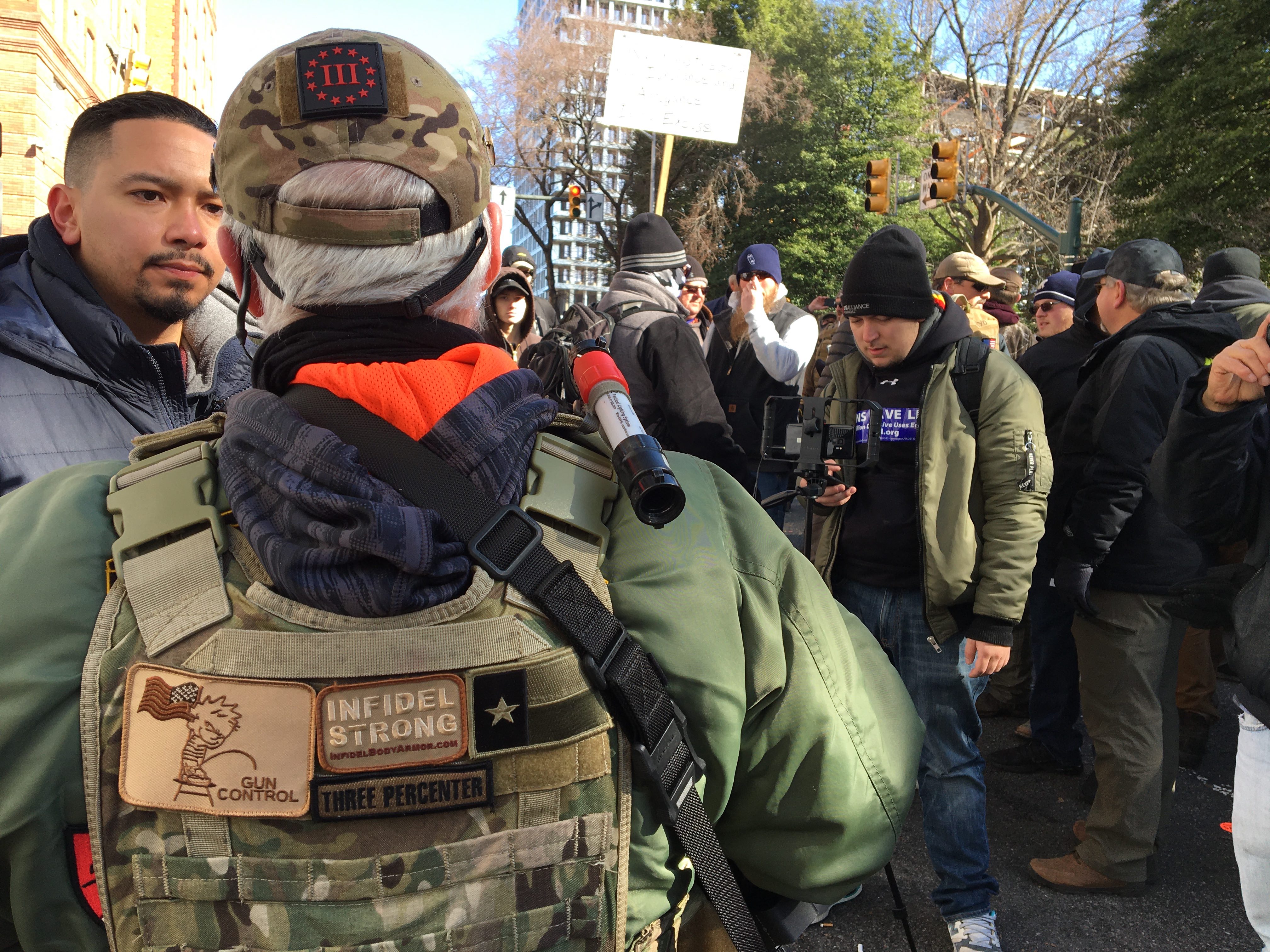 One protester in military garb wears patches with far-right III Percenter emblems on his vest and hat. (Sheren Khalel/MEE) 
