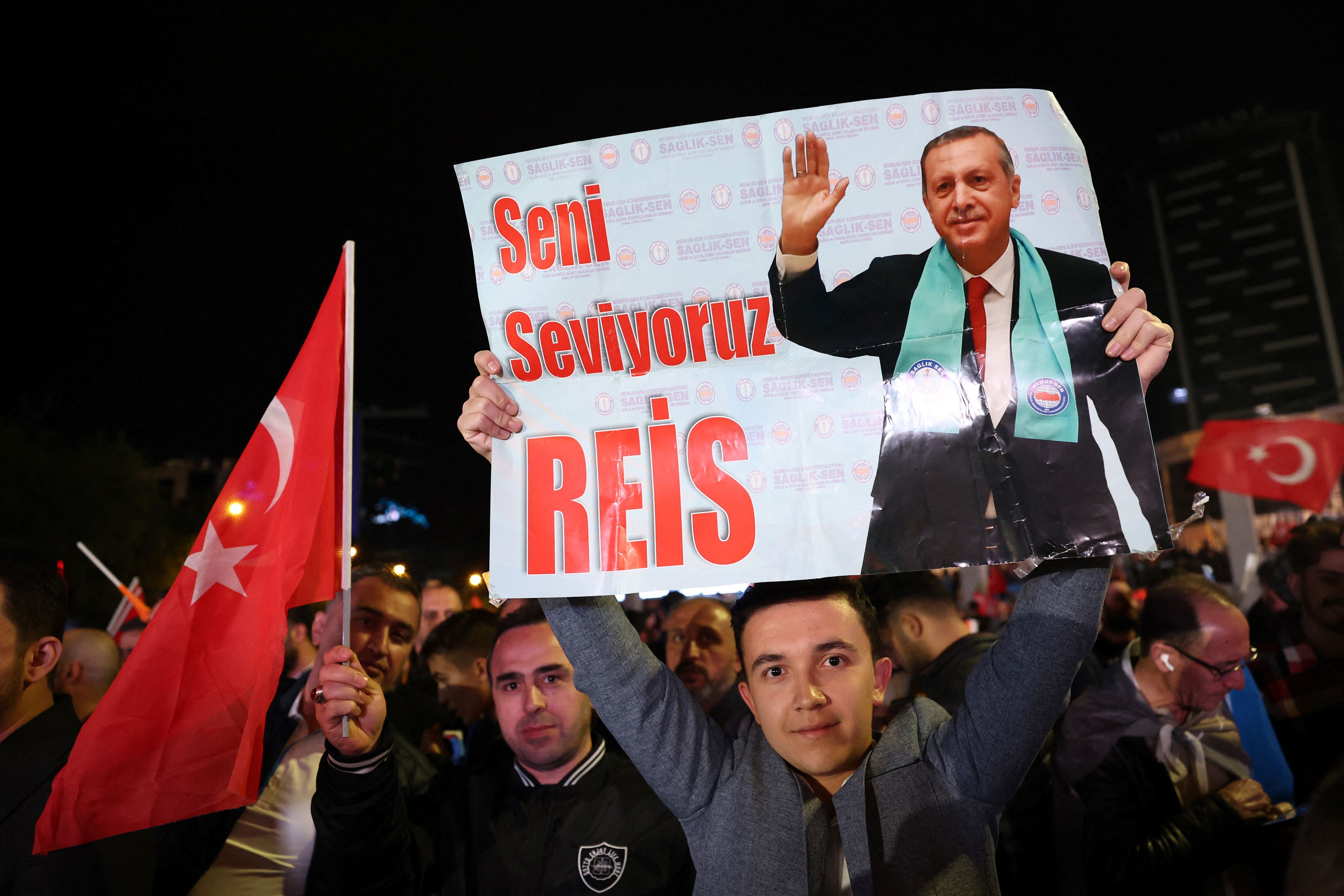 A supporter of Turkish President Recep Tayyip Erdogan holds a poster which reads 'We Love You Chief' outside the AKP headquarters after polls closed (AFP)
