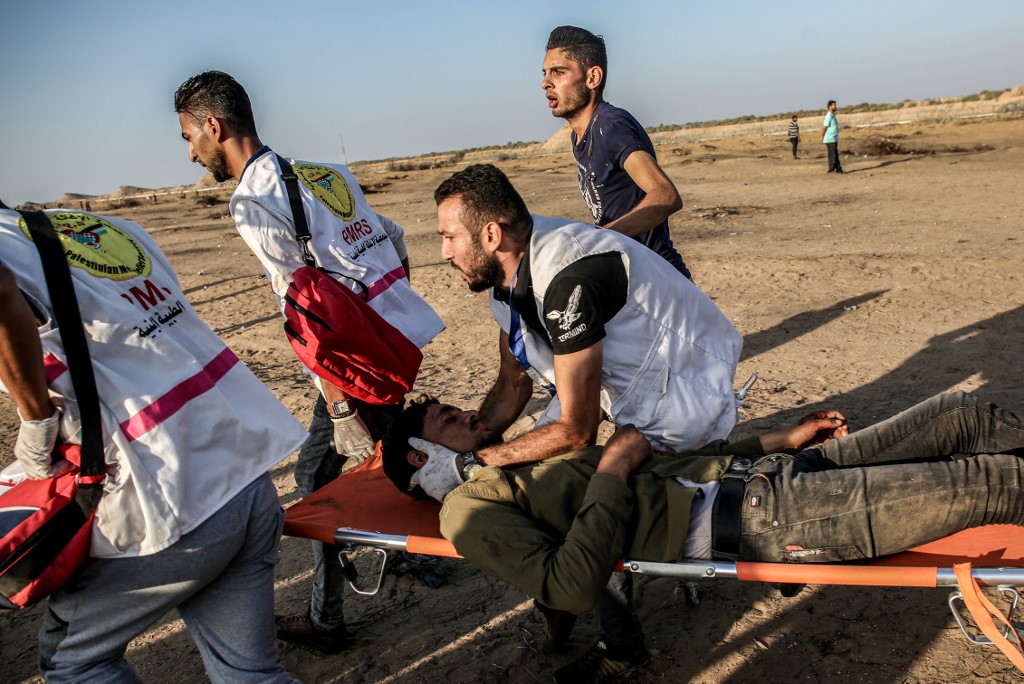 Palestinian paramedics carry an injured protester in Gaza on 27 September (AFP)