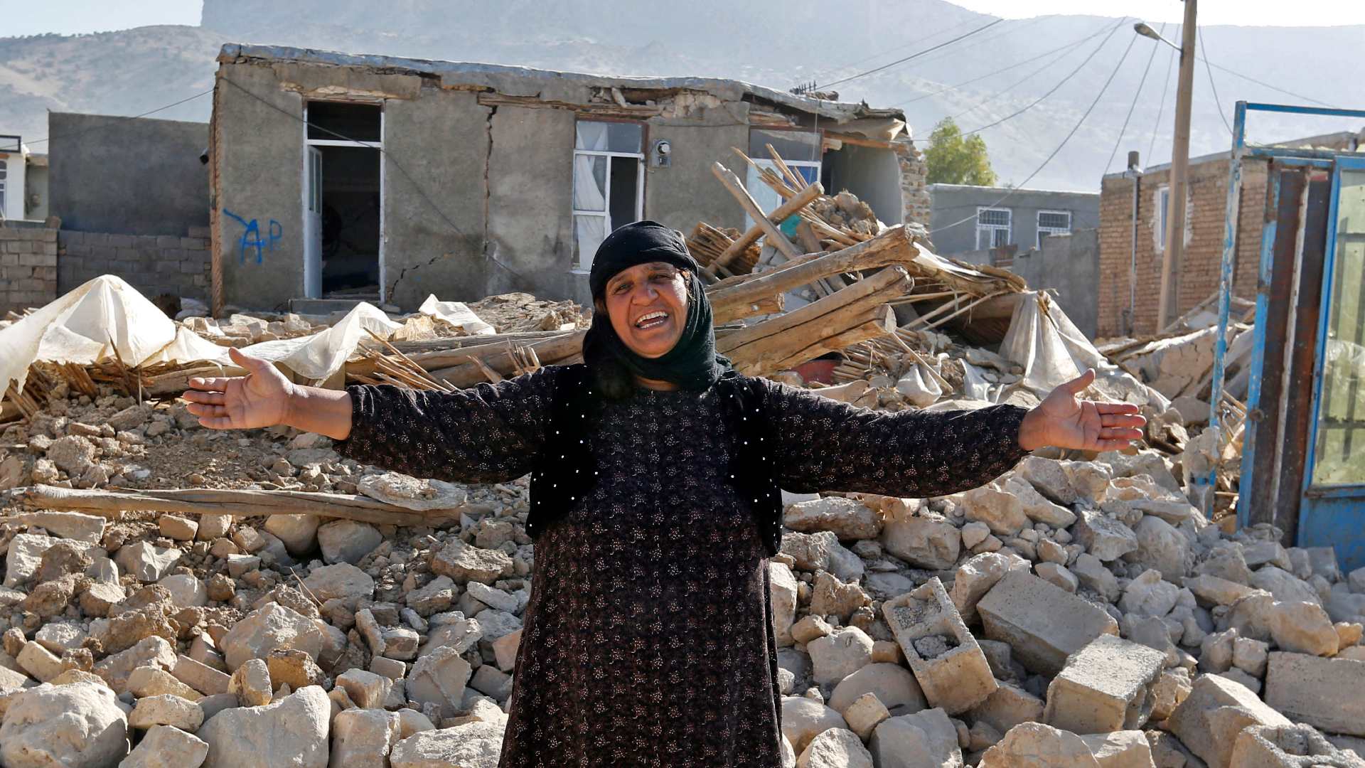 A woman stands in front of the rubble of her home in Iran's Kermanshah province following an earthquake in November 2017 (AFP)