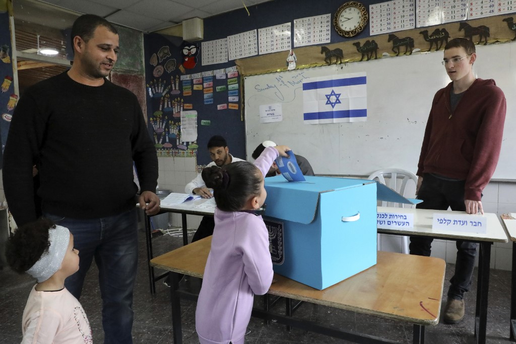 An Arab-Israeli girl casts her father’s ballot in Rahat on 2 March (AFP)