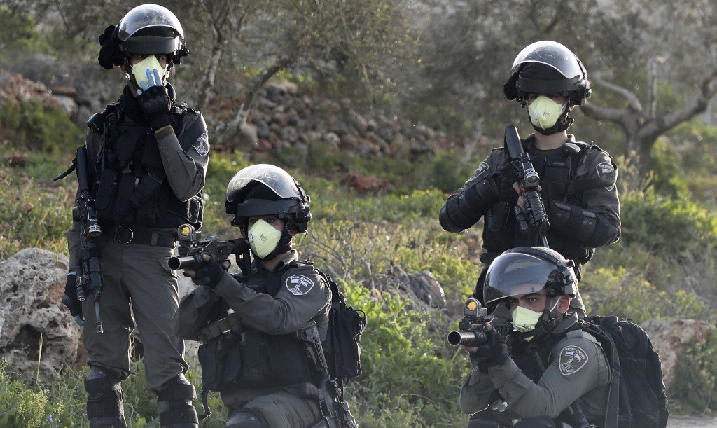 Des membres de la police des frontières israélienne visent des jeunes palestiniens lors de troubles en Cisjordanie occupée, le 11 mars (AFP)