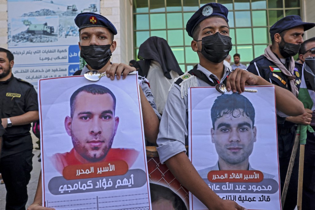 Palestinian boy scouts hold up portraits of two of the six escaped Palestinian prisoners during a rally in solidarity with them in Gaza on 8 September 2021 (AFP)