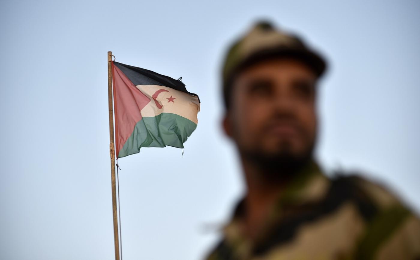 A soldier wearing the Polisario Front uniform stands by a Sahrawi flag in 2017 (AFP)