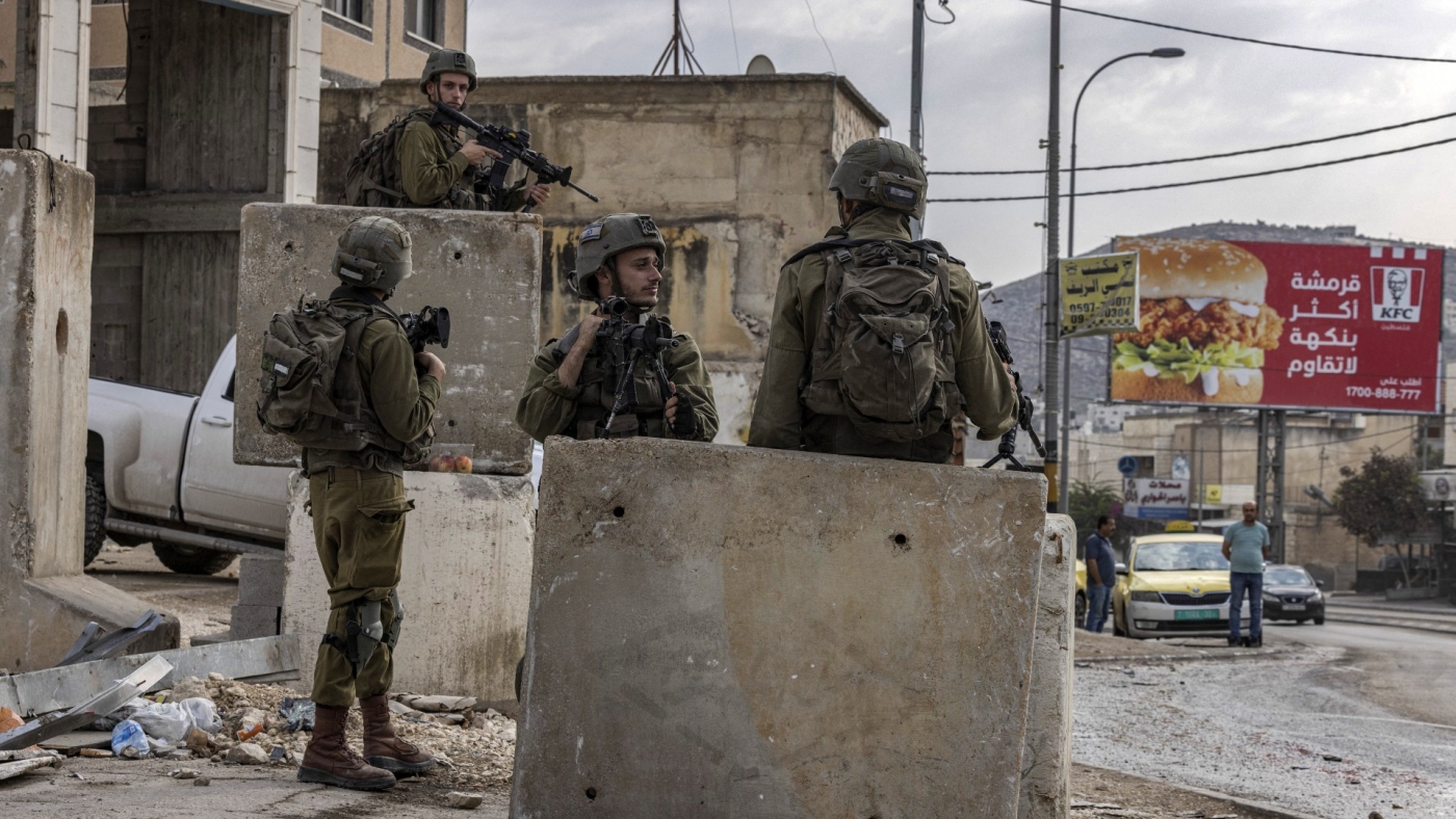 Israeli soldiers stand guard in the Palestinian village of Huwara, south of Nablus in the occupied West Bank on 26 October 2022 (AFP)