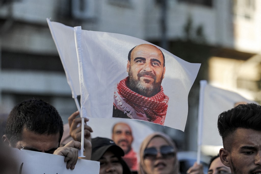 Demonstrators hold up images of late Palestinian activist Nizar Banat as they march during a protest in the city of Hebron in the occupied West Bank on 13 July 2021 (AFP)