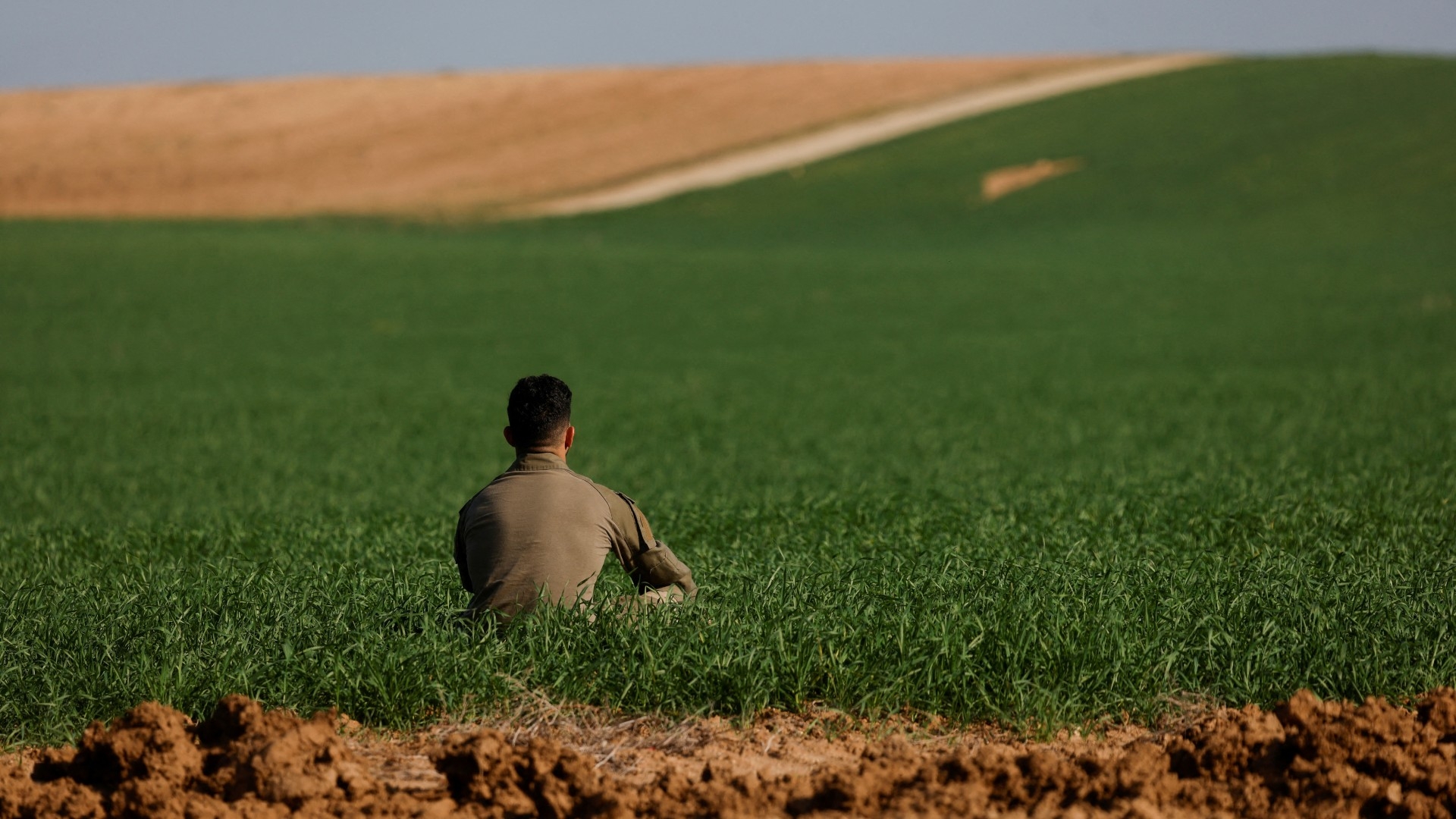An Israeli soldier sits in a field near the Israel-Gaza boundary, in Israel, 30 December (Reuters/Amir Cohen)