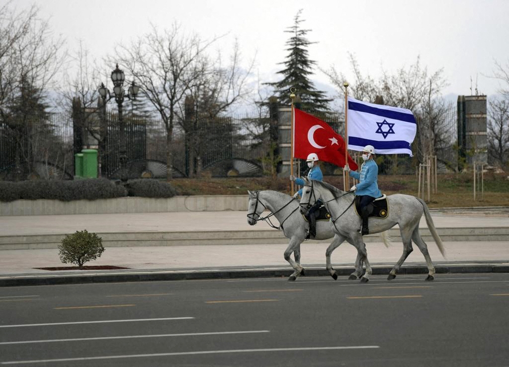 A handout picture obtained from the Israeli Government Press Office (GPO) on March 9, 2022, shows Turkish cavalry guards waving the Israeli (R) and Turkish flags, to welcome the Israeli president in the capital Ankara. (AFP)