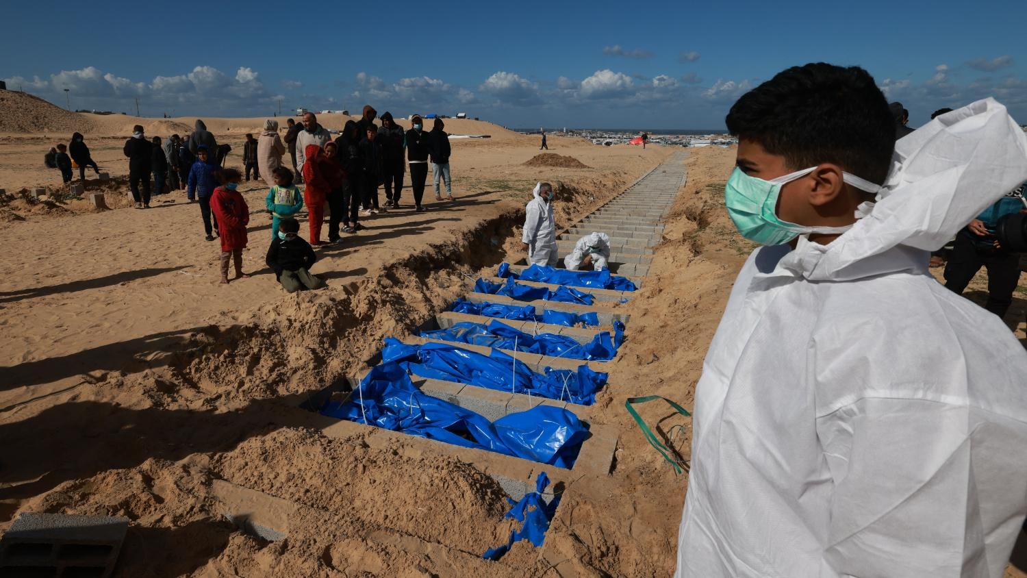 Palestinian Health Ministry workers bury the bodies of unidentified Palestinians after they were returned by Israel, at a mass grave east of Rafah in southern Gaza on 30 January 2024.