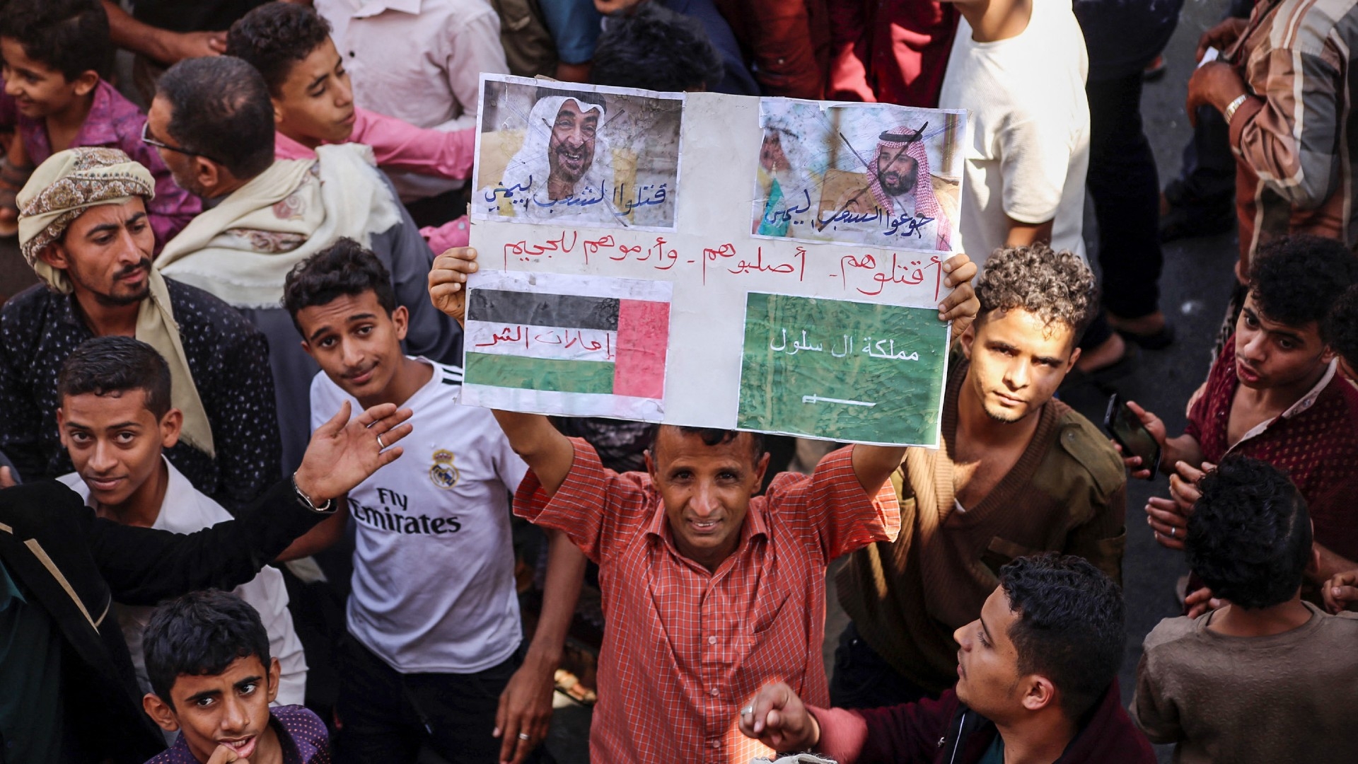 A Yemeni protester holds up a sign showing the crossed-out faces of the Saudi Crown Prince Mohamed bin Salman (R) and Emirati President Mohamed bin Zayed (L) in the southwestern Yemeni city of Taiz on 4 October 2018 (AFP/Ahmad al-Basha)
