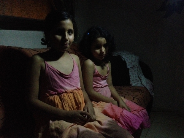 Deena and her younger sister Ala wait in the dark as bombs fall (MEE / Mohammed Omer) 