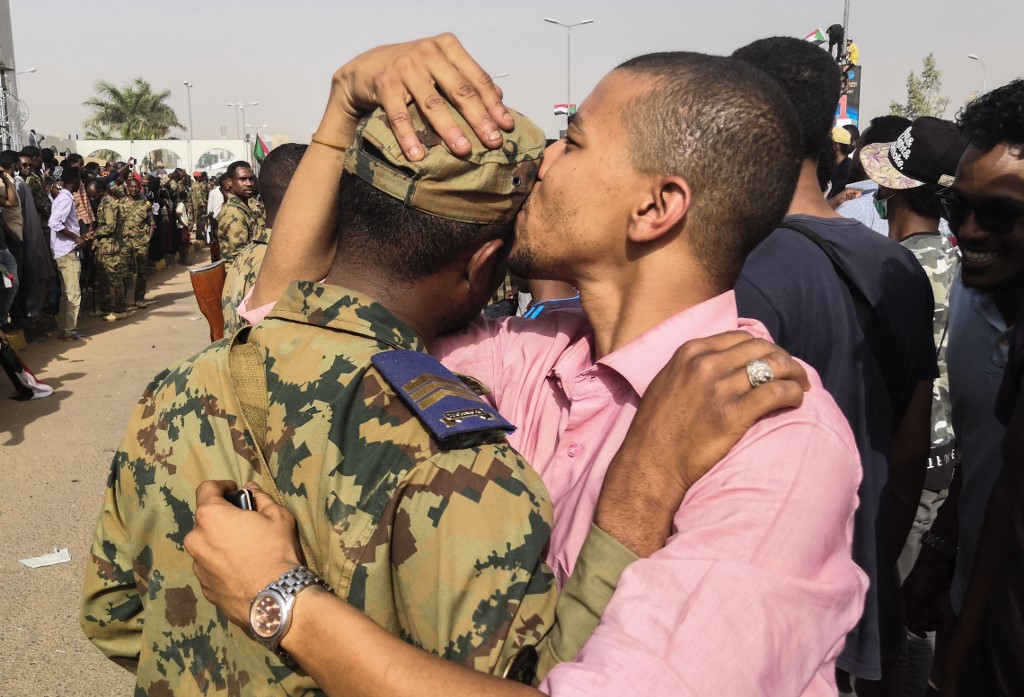 A Sudanese protester kisses a soldier on 11 April in Khartoum (AFP)