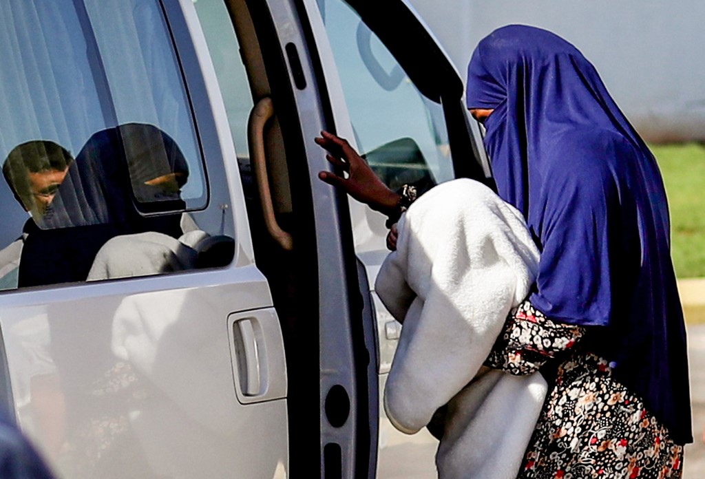 A Sudanese woman who allegedly belonged to IS is escorted into a vehicle in northeastern Syria after being handed over to Sudanese diplomats in September 2018 (AFP) 