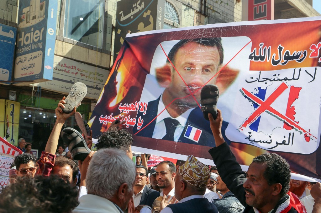 Demonstrators lift a banner depicting Macron as a pig in Taiz, Yemen, on 31 October (AFP)