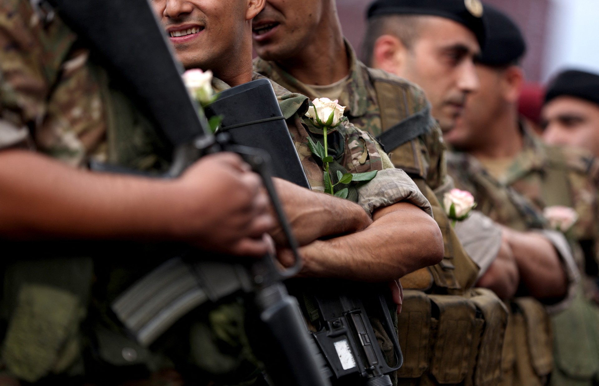 Lebanese army soldiers carry roses offered to them by anti-government protesters in the area of Jal al-Dib, on 23 October, 2019 (AFP)