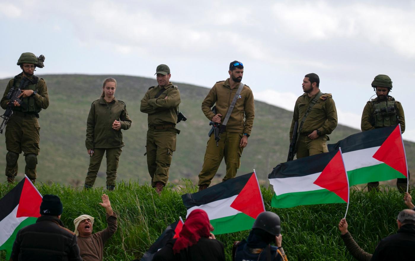 sraeli soldiers stand at attention as Palestinian demonstrators take part in a protest against the annexation of the Jordan Valley, in the village of Tammun (AFP)