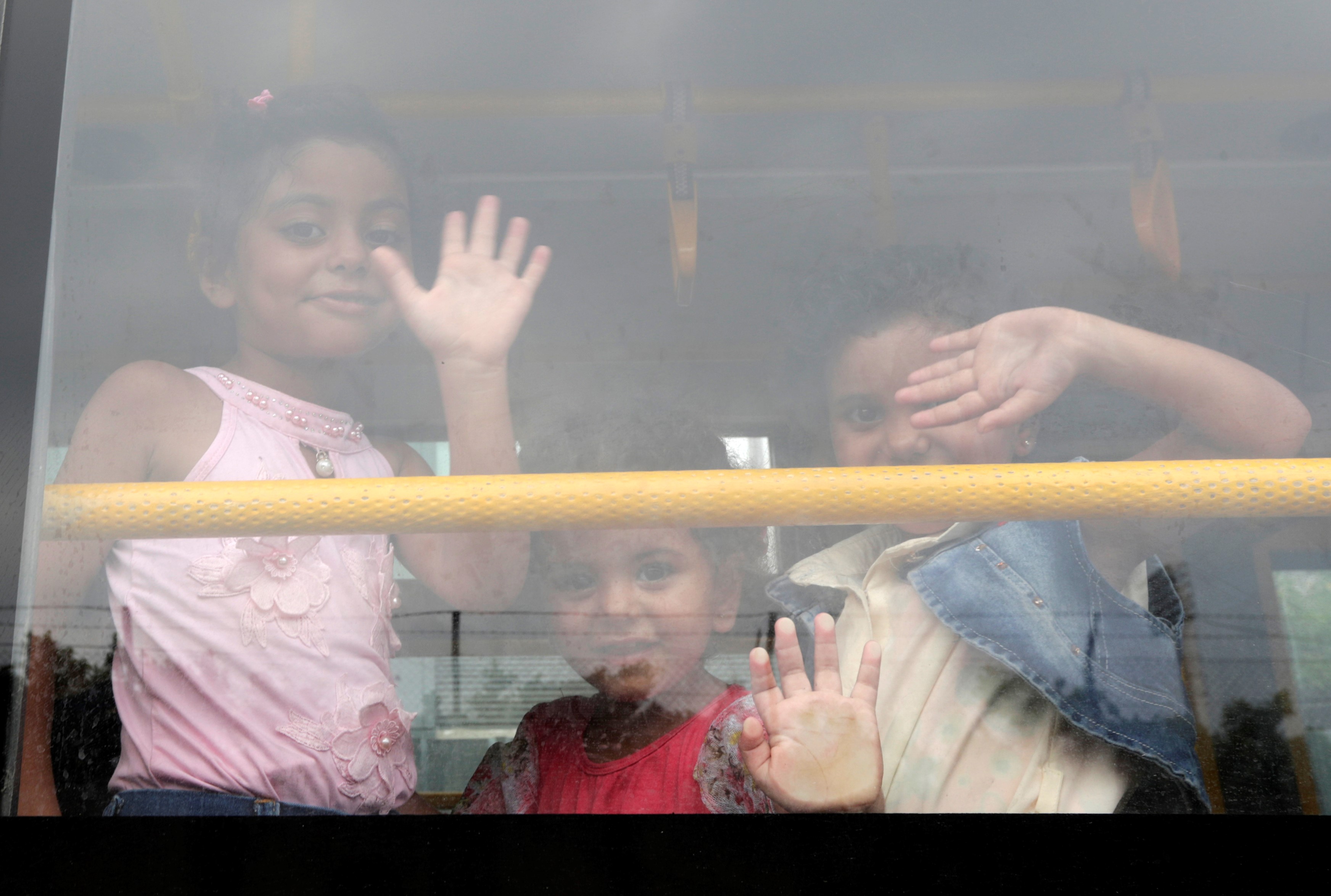 Syrian refugees wave from on board a bus in the Beirut suburb of Burj Hammoud, north of the capital on 29 August (AFP)