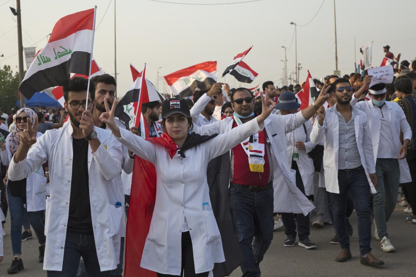 Iraqi doctors and pharmacists flash the victory sign and wave their country's national flags in Basra on 30 October (AFP)