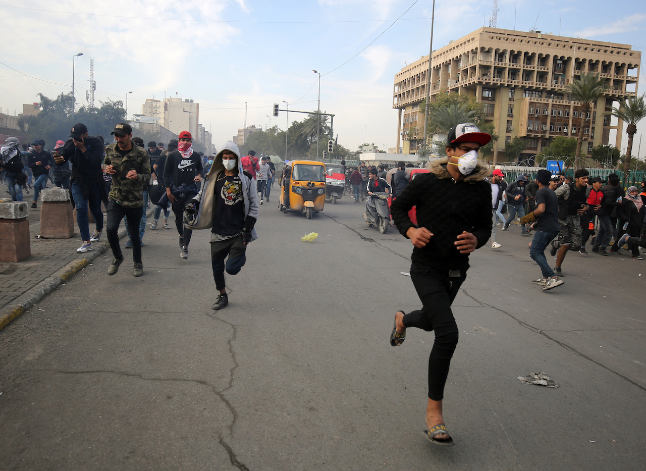 Iraqi protesters run for cover during clashes with riot police following a demonstration in Al-Khilani Square in the capital Baghdad (AFP)