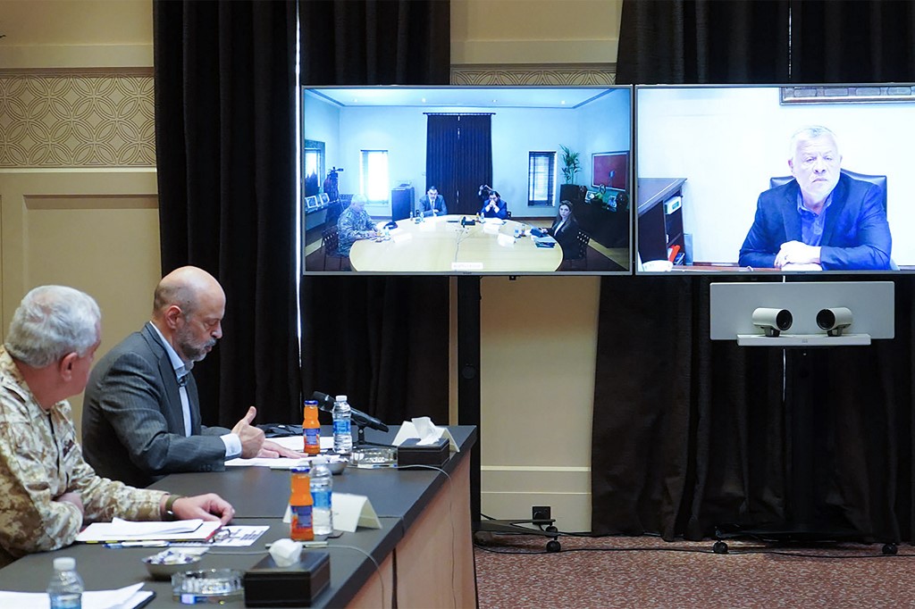 Le roi Abdallah II de Jordanie (sur l’écran de droite) tient une réunion en vidéoconférence avec des représentants du gouvernement, y compris le Premier ministre Omar Razzaz (2e à gauche) sur la crise du coronavirus (Yousef Allan/Palais royal jordanien/AFP)