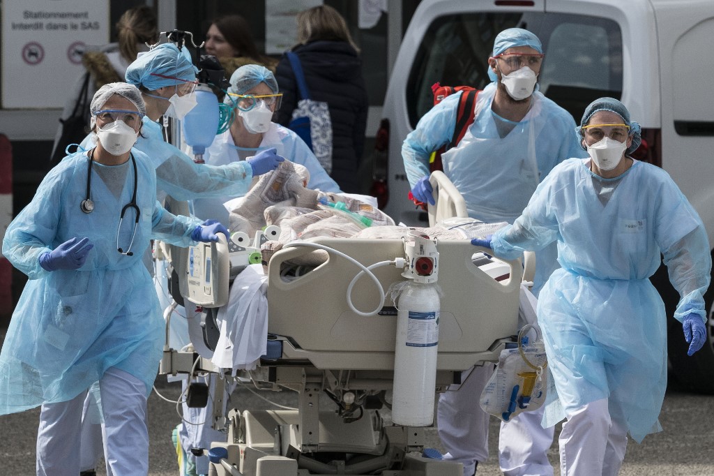Un patient atteint du COVID-19 est transporté vers un hélicoptère médicalisé devant l’hôpital Émile Muller de Mulhouse, dans l’est de la France, pour être évacué vers un autre établissement hospitalier, le 22 mars 2020 (AFP)