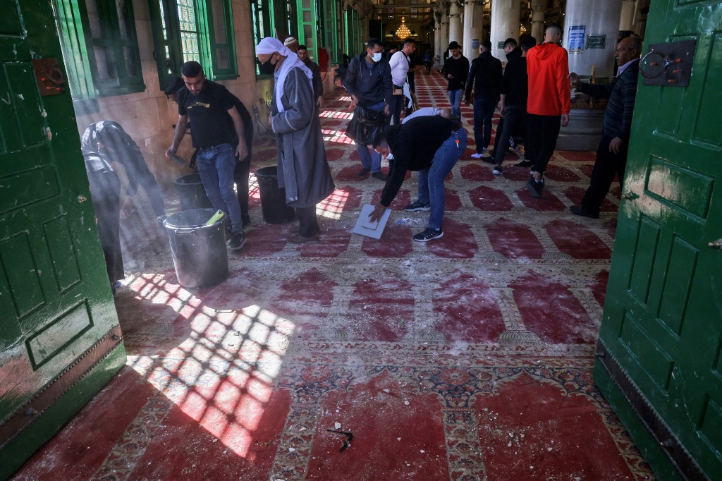 Muslim worshippers clean-up debris following Israeli raid in Al-Aqsa Mosque on 15 April 2022. (AFP)