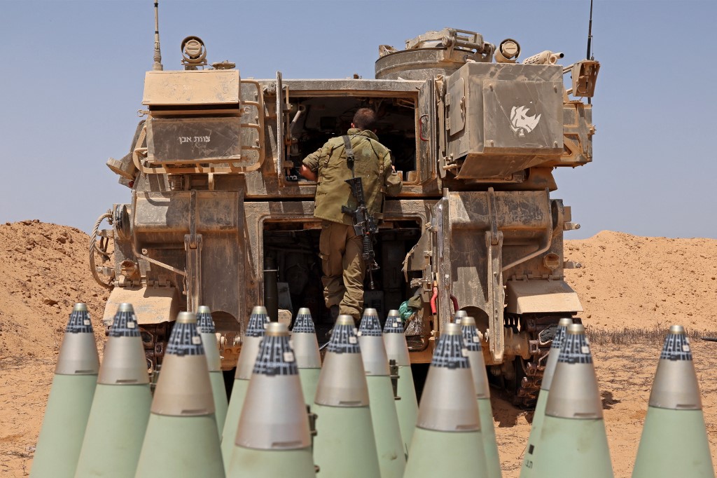 An Israeli soldier lines up artillery shells along the border with Gaza, on 6 August 2022 (AFP)
