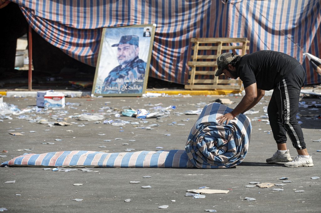 A supporter Muqtada al-Sadr rolls a mattress to be folded as their encampment in Baghdad's Green Zone is dismantled on 30 August 2022 (AFP)