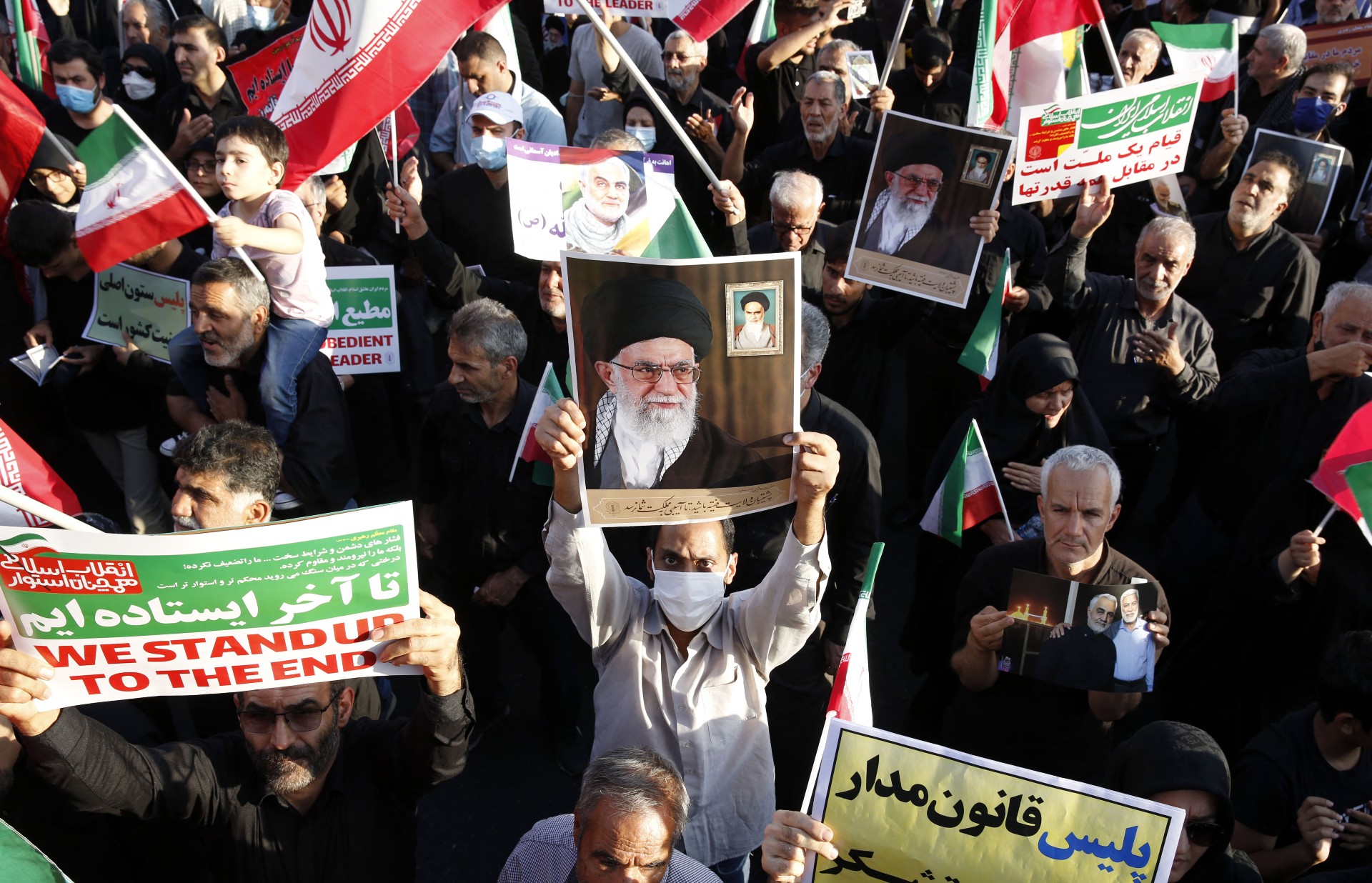 Pro-government protesters hold pictures of Supreme Leader Ayatollah Ali Khamenei during a rally against the recent demonstrations, in Tehran, on 25 September (AFP)