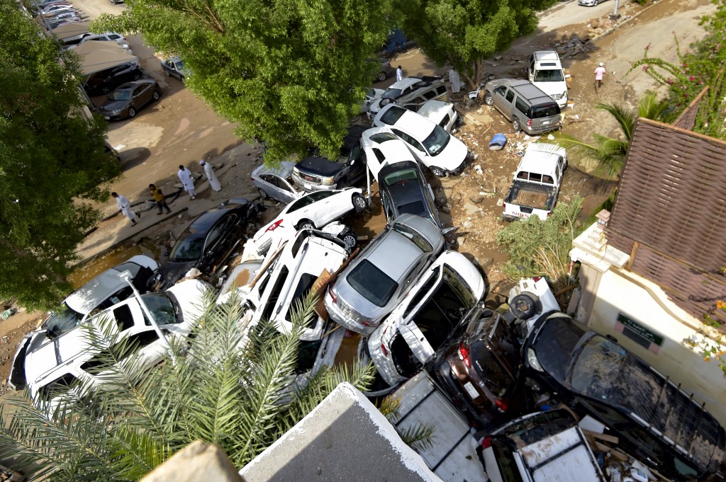 Cars that were washed away by heavy rains are piled up in an alley in the Saudi coastal city of Jeddah on 25 November 2022 (AFP)