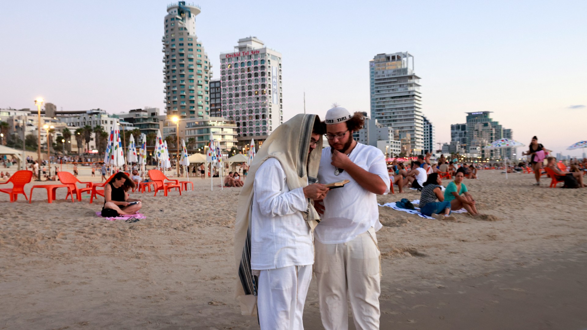 Des religieux lisent un livre sur la côte de Tel Aviv (AFP)