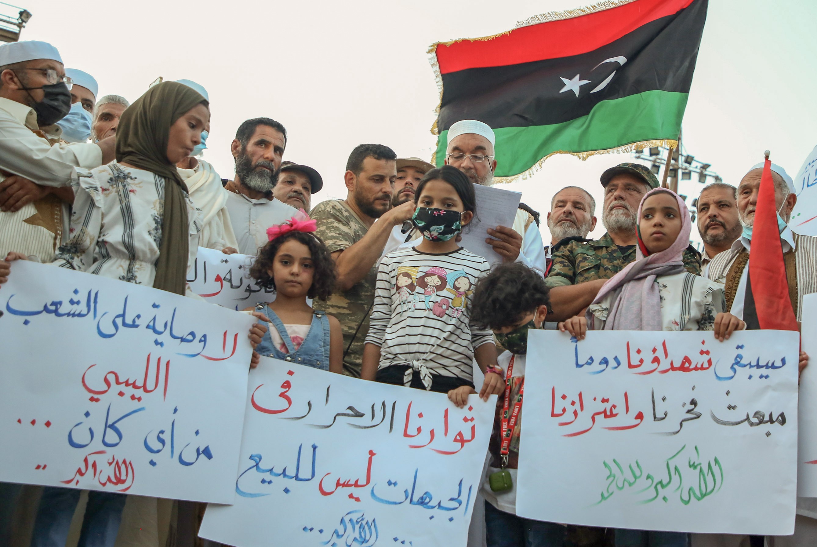 Libyan demonstrators lift placards and national flags during a rally in Martyrs Square in the capital Tripoli, to protest the deteriorating political, security, and living conditions in the country, on October 2, 2020.