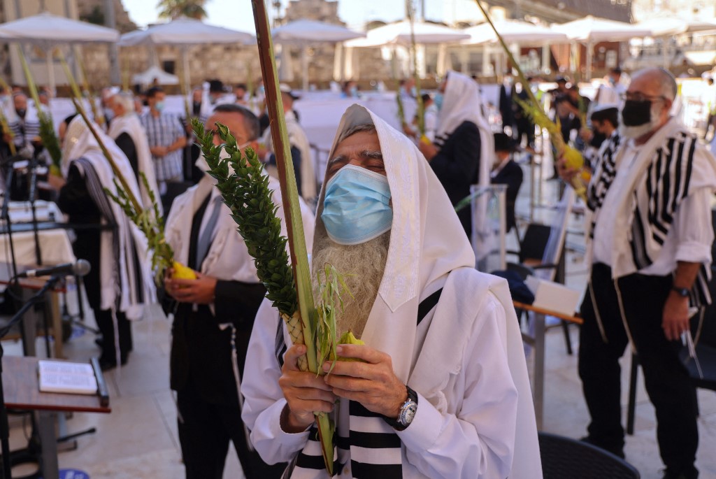 Un juif prie, en tenant les quatre espèces de plantes importantes pour Souccot (AFP)