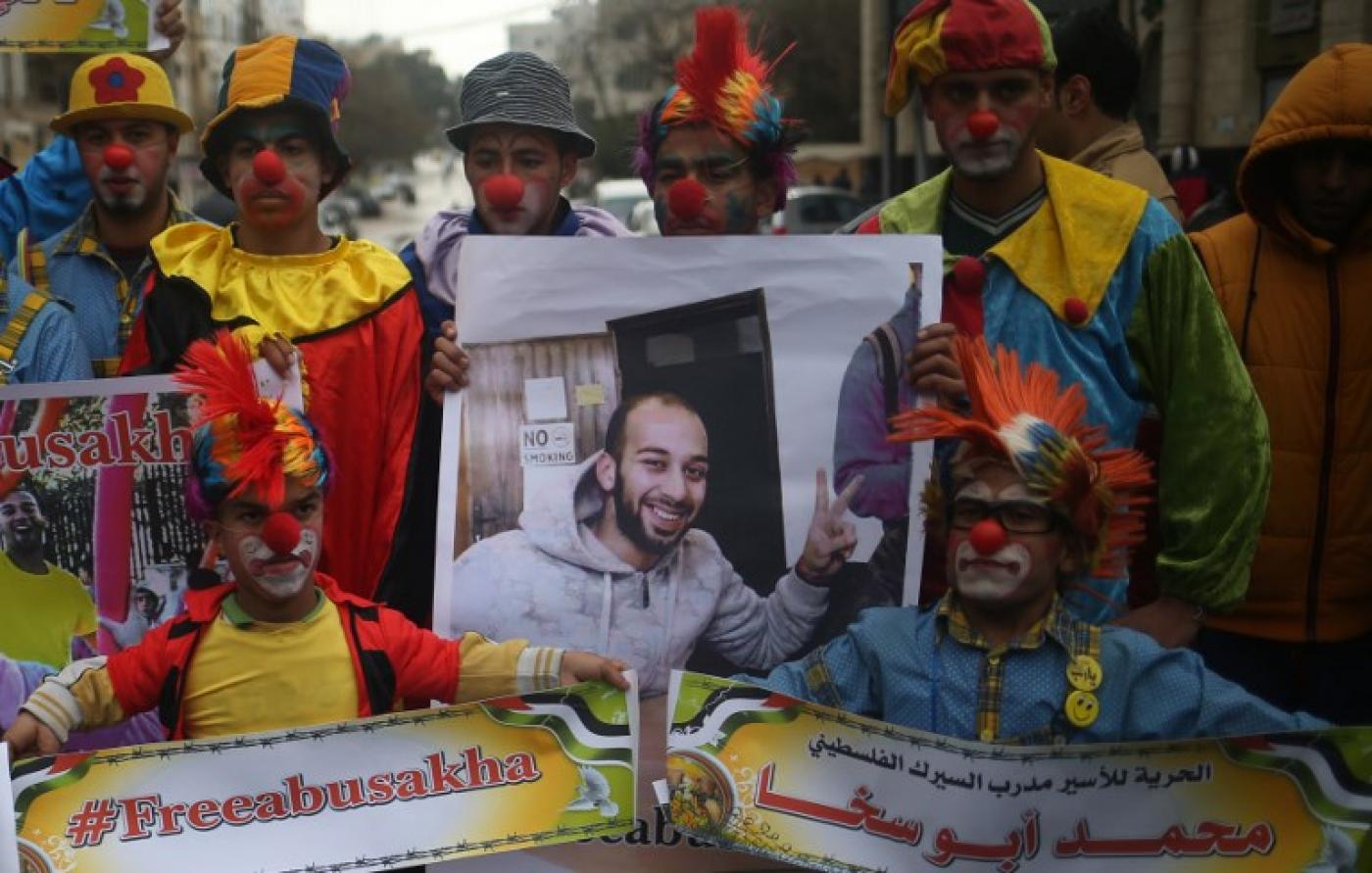 Des clowns palestiniens tiennent des portraits de leur collègue emprisonné Mohammed Abu Sakha lors d’une manifestation de solidarité en février 2016 à Gaza (AFP)