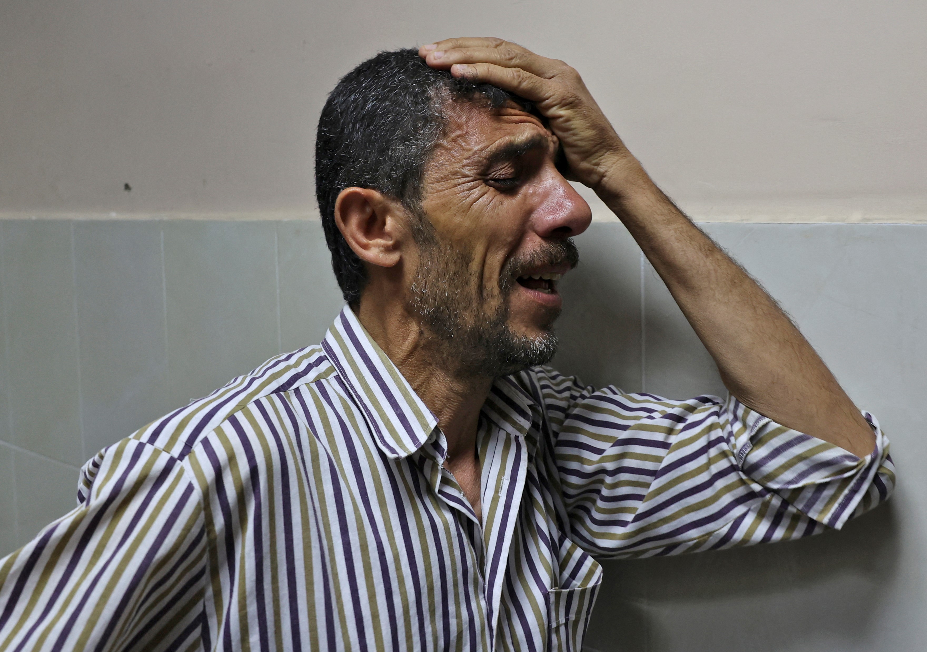 Mahmoud Obeid carries mourns his 7-year-old daughter Butheina, who was killed during an Israeli airstrike last night, at the morgue of the Indonesian hospital in Beit Lahia, in the northern Gaza Strip, on 16 May, 2021 (AFP)