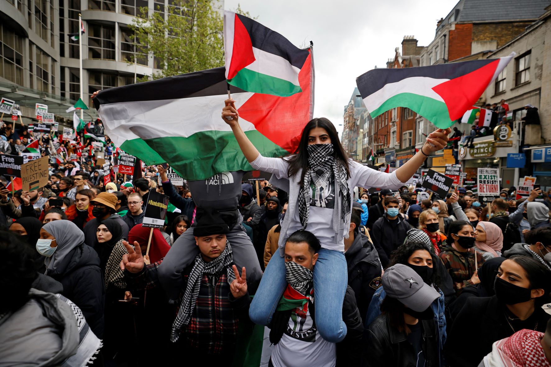 Pro-Palestinian activists and supporters wave flags and carry placards during a demonstration in support of the Palestinian cause outside the Israeli Embassy in central London on May 15, 2021 (AFP)