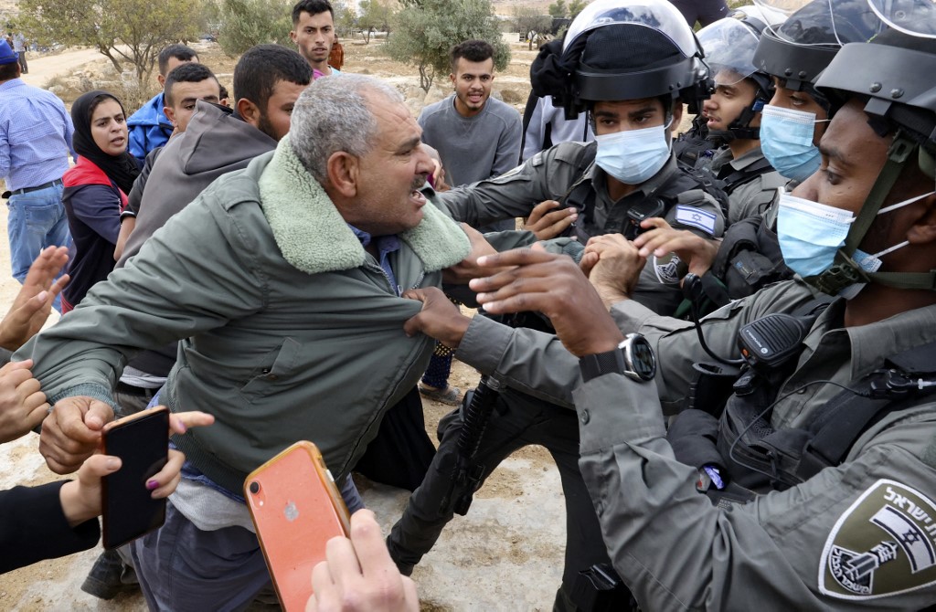 Israeli security forces stop a Palestinian man from the village of Susya during scuffles with Jewish settlers