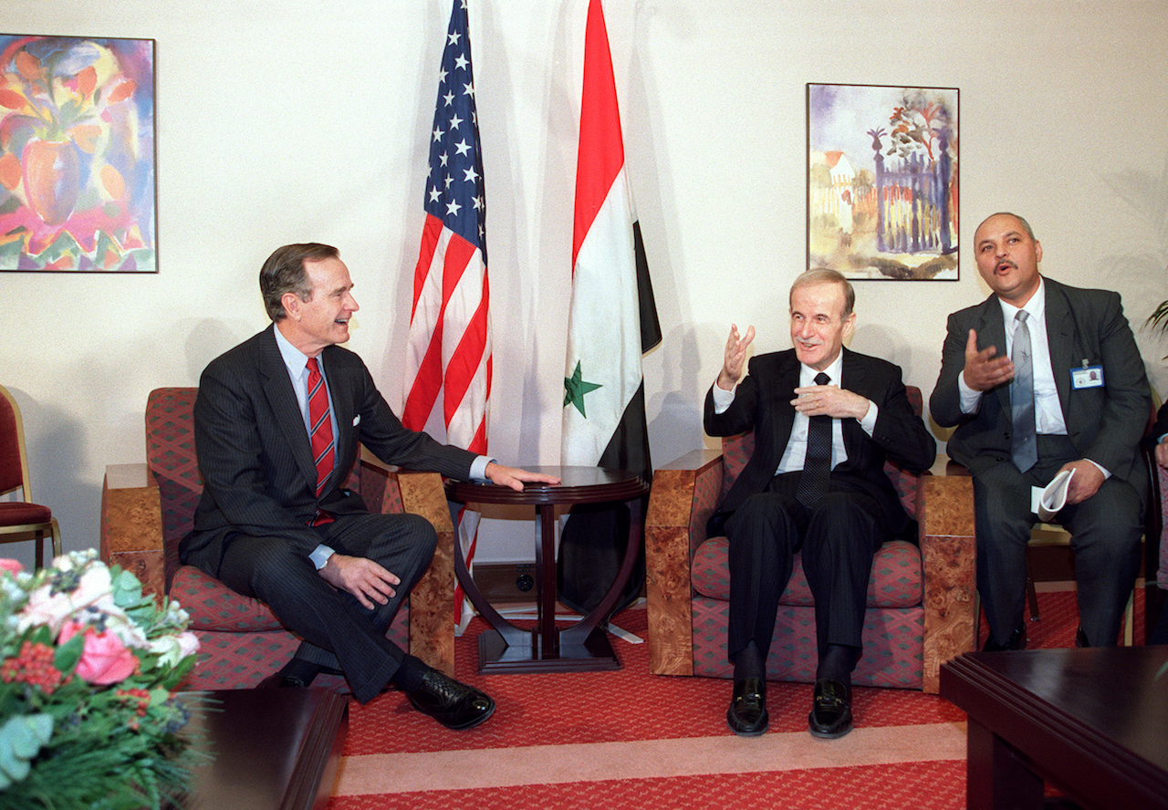 US President George Bush (L) shares a joke with Syrian counterpart Hafez el Assad prior to their private meeting held at the Holiday Inn Crown Plaza, here 23 November 1990 (AFP)