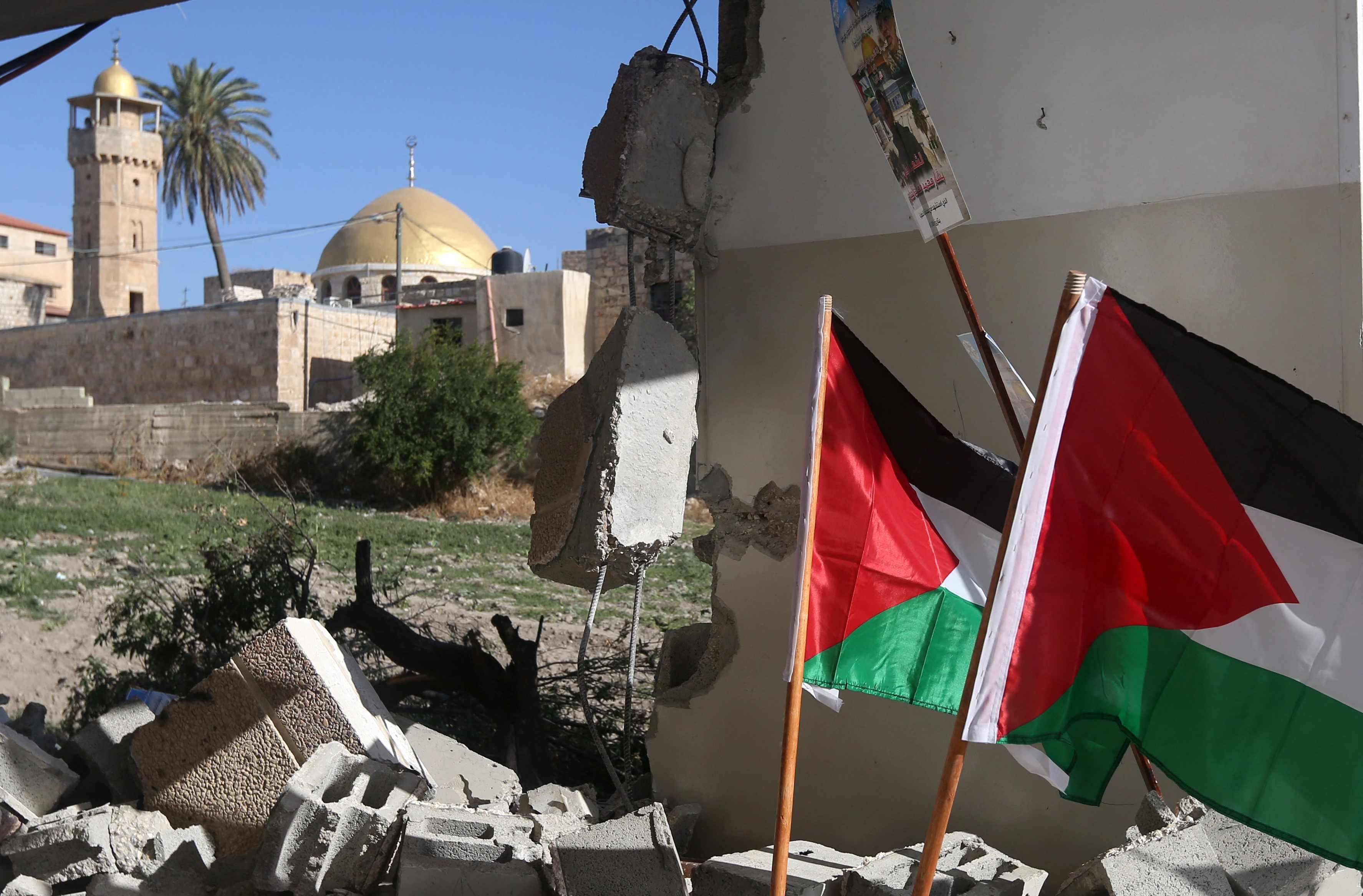   Palestinian flags are seen placed on the rubble of a house in the village of Haja, in the Israeli-occupied West Bank on 21 June, 2016 (AFP)