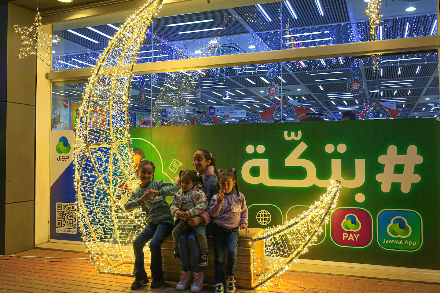 Palestinian children pose in front of a mall decorated in preparation for the month of Ramadan in the centre of Gaza City, on 18 March 2023 (Photo: Samar Abu Elouf, supplied by author)