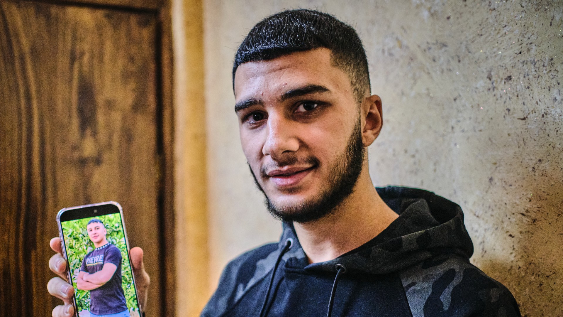 Wael Mesheh, 17, spent 14 months in Israeli prison. He holds up a photo of him looking much larger before his arrest (MEE/Angelo Calianno)