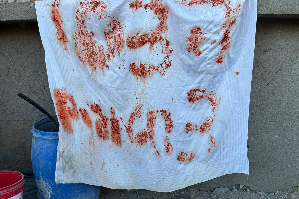 Une pancarte de fortune indiquant en hébreu « Au secours, 3 otages » utilisant des restes de nourriture qui auraient été montrés par des otages israéliens avant d'être abattus par des soldats israéliens, 17 décembre 2023 (AFP)