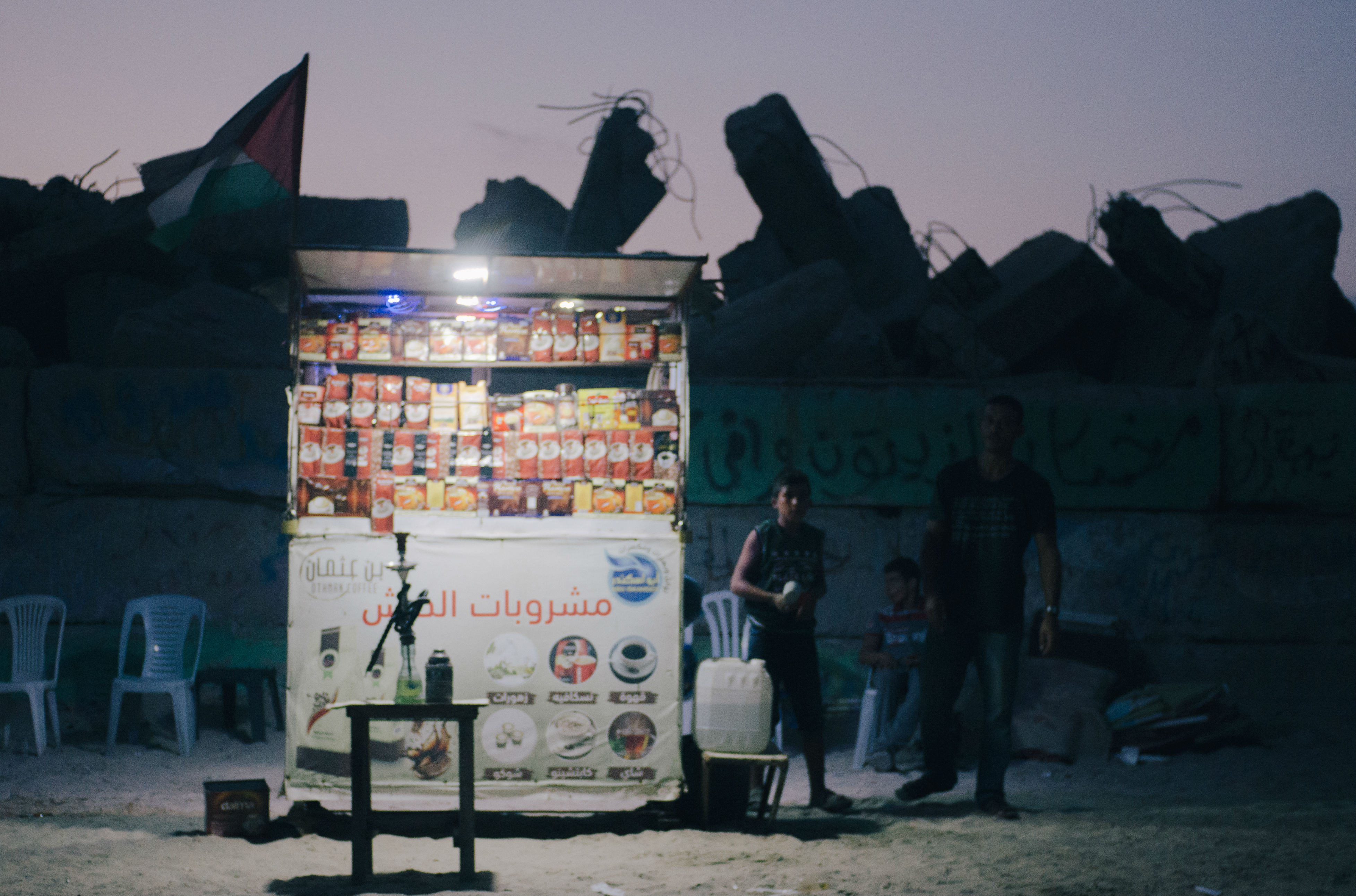 As the sun sets on Gaza, little pinpricks of light begin dotting the darkened coastline. Battery-powered LEDs fastened to coffee stalls cut against the night in the power-starved enclave, the only source of illumination for teen vendors preparing for nightly gatherings by the sea