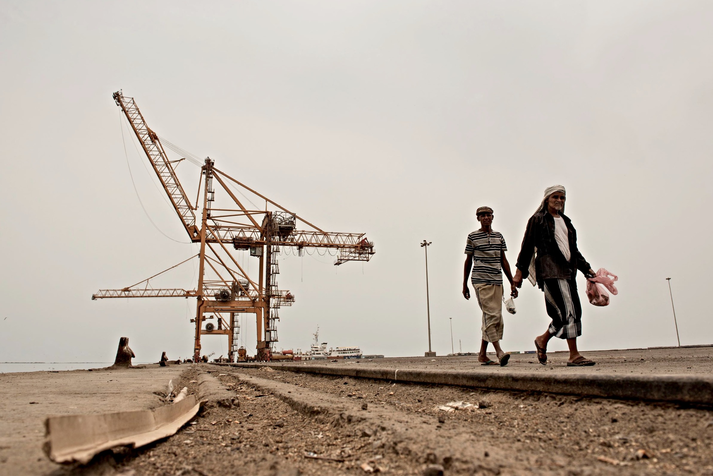 People walk near damaged cranes in Hodeidah port in Yemen (Alessio Romenzi)