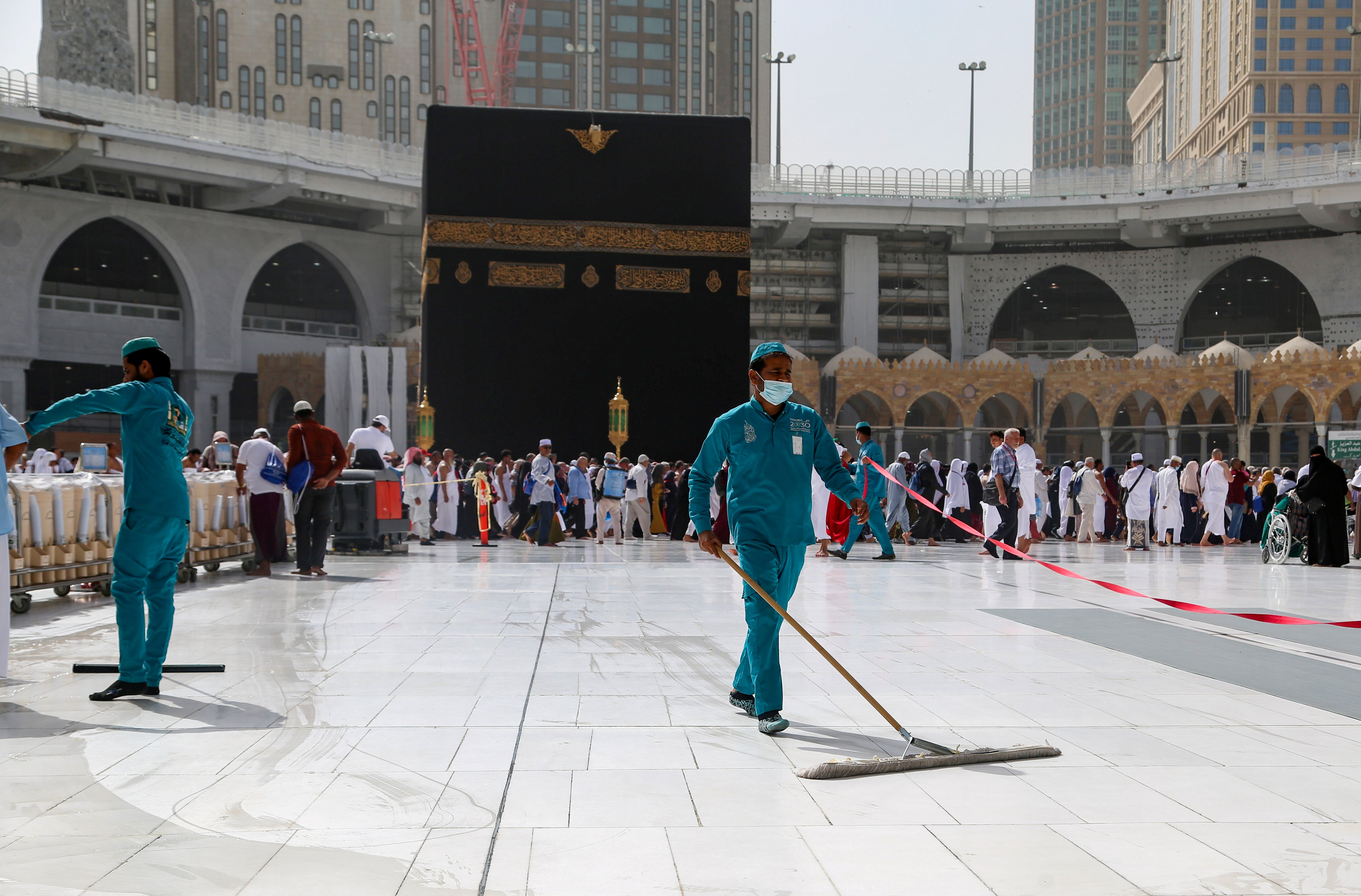 Cleaners wear protective face masks, following the outbreak of the coronavirus, as they swipe the floor at the Kaaba in the Grand mosque in the holy city of Mecca, Saudi Arabia March 3, 2020.