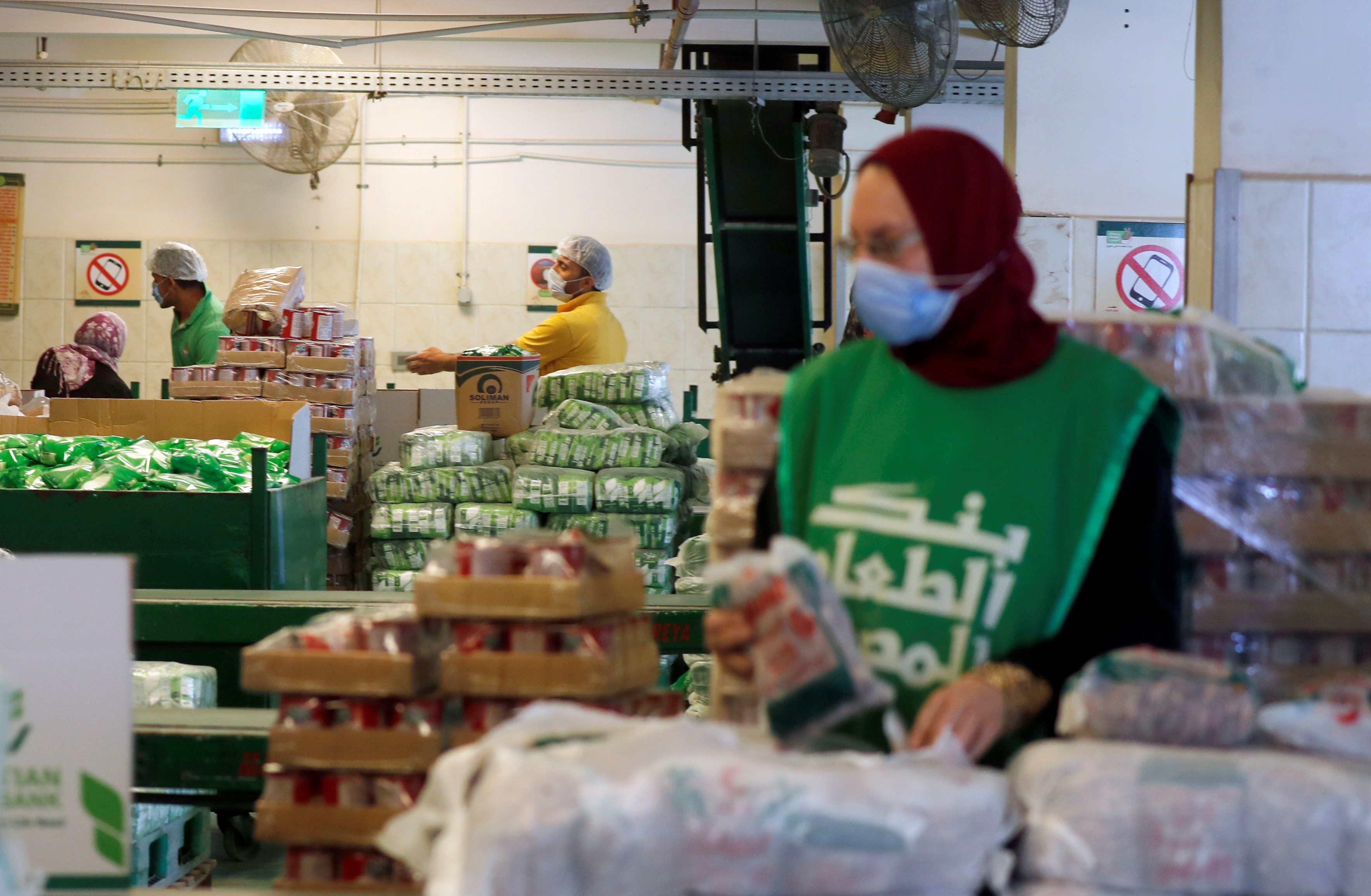Workers of the Egyptian Food Bank fill boxes with food and aid for needy families 